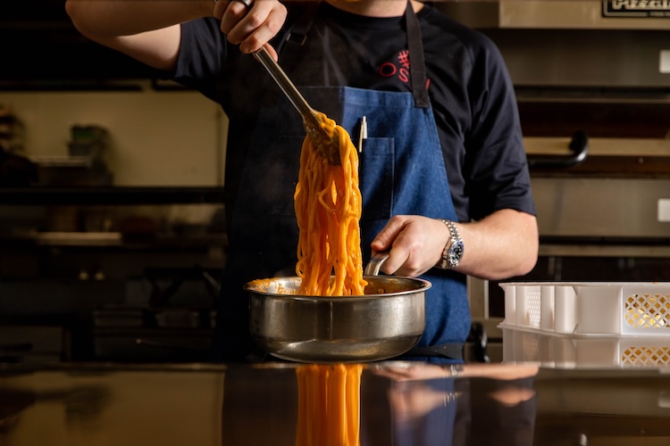 Pasta being prepared by a chef in a large metal pot